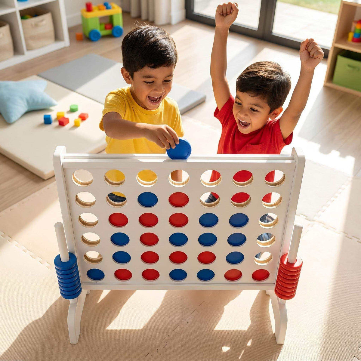 Montessori XXL 4 op een Rij met wit speelbord, rode en blauwe kunststof schijven en stevige poten; kinderen spelen samen.